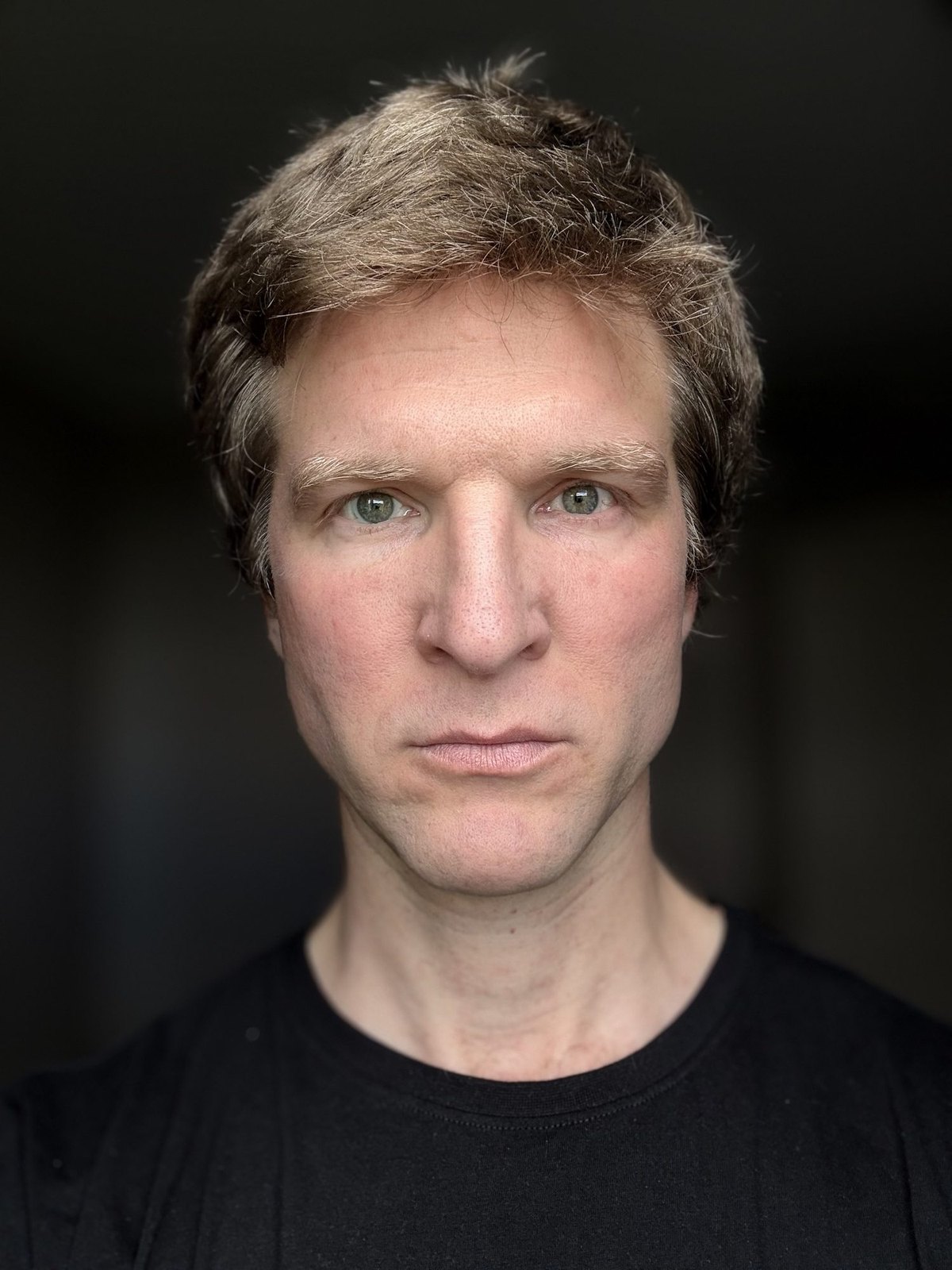 Portrait de Dominique Engelhardt, gros plan sur fond sombre, regard intense